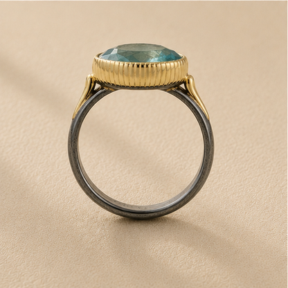 Two-tone apatite ring top view: oval blue-green stone in ribbed gold bezel on dark silver band