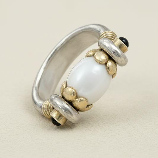 Silver and gold ring with a large white bead on a white background