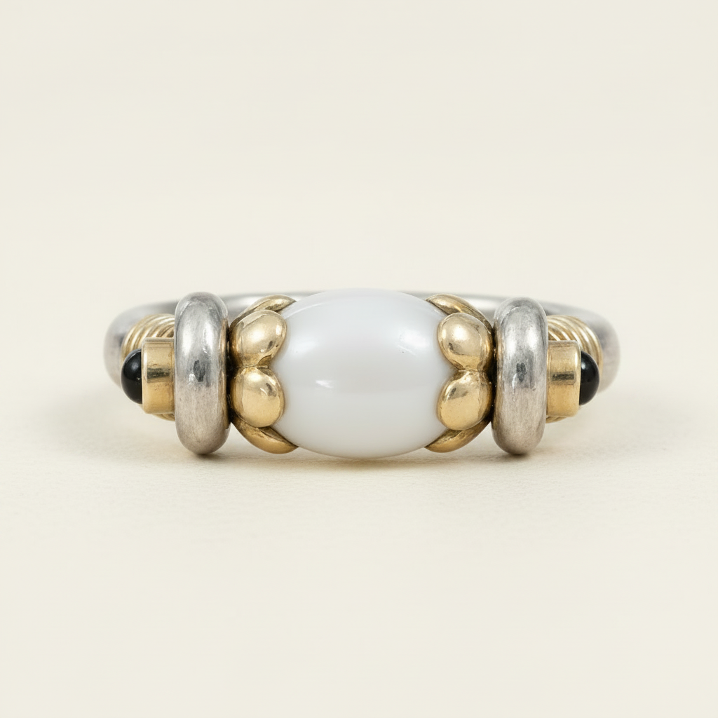 Beaded ring with white central bead, gold accents, and black beads on a white background