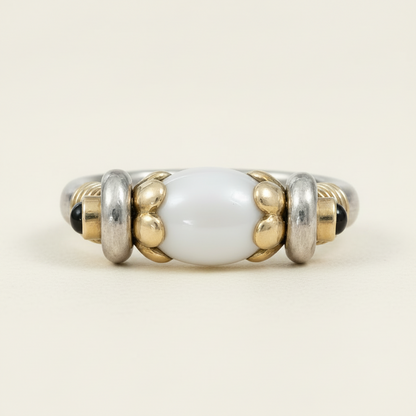 Beaded ring with white central bead, gold accents, and black beads on a white background