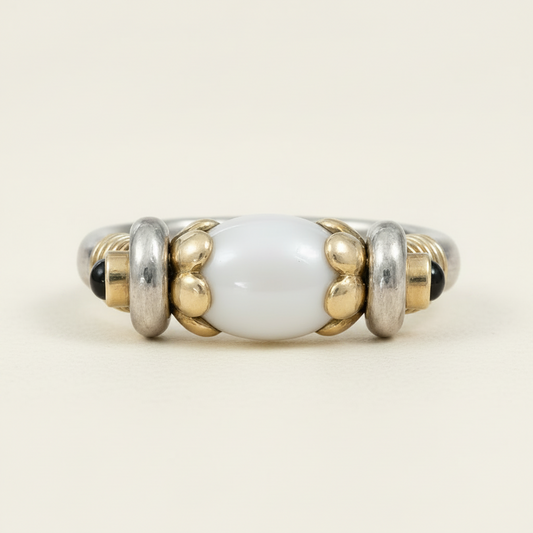 Beaded ring with white central bead, gold accents, and black beads on a white background