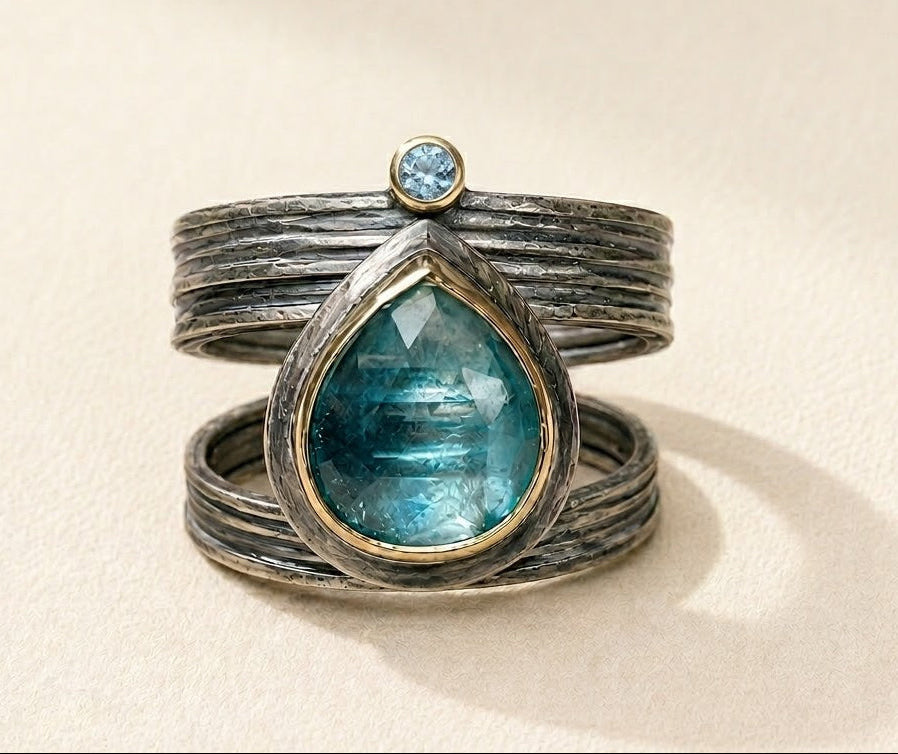 Silver cuff-style ring with large teal teardrop gemstone and small round blue stone
