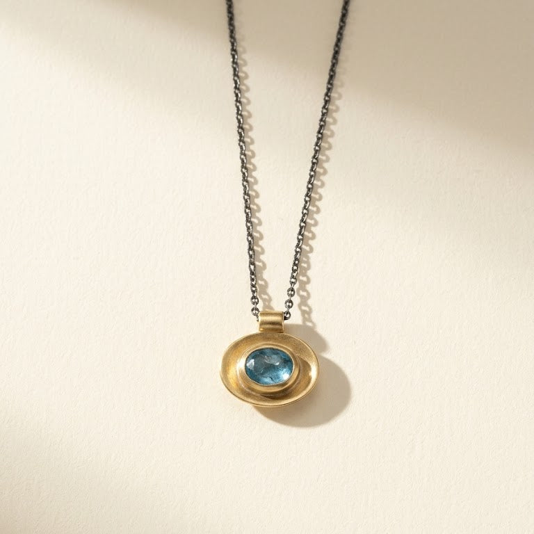 Gold oval well pendant necklace with blue center stone on fine silver chain