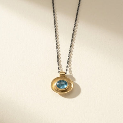Gold oval well pendant necklace with blue center stone on fine silver chain