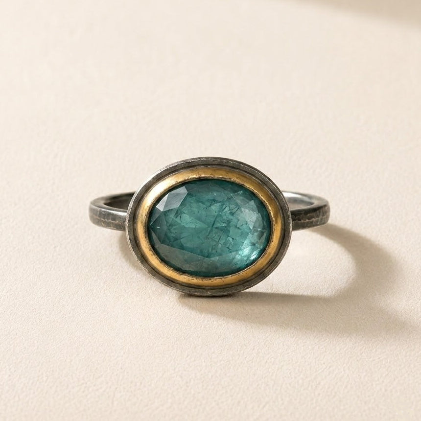 Oval teal gemstone ring with gold rim bezel and slim silver-tone band