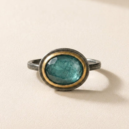 Oval teal gemstone ring with gold rim bezel and slim silver-tone band