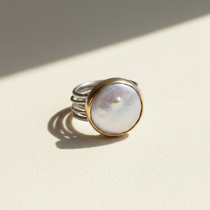 Nomad dancing pearl ring with opalescent round pearl, silver band, and gold bezel